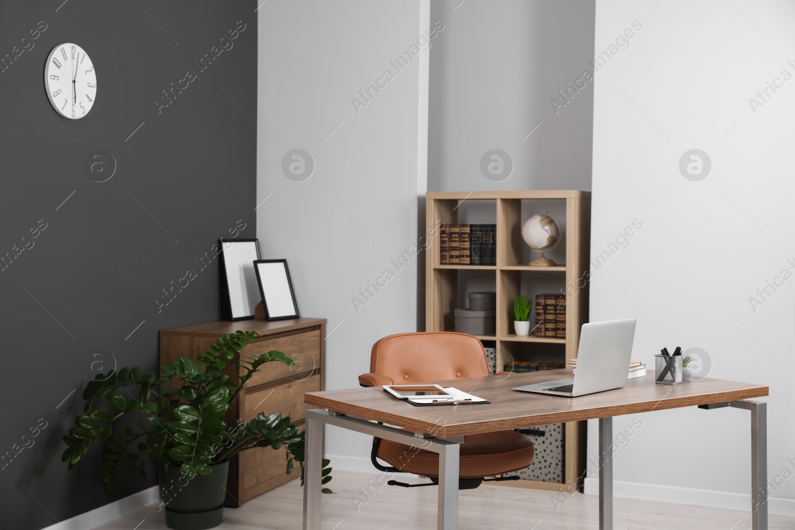 Photo of Stylish office with modern furniture and laptop on wooden desk. Interior design