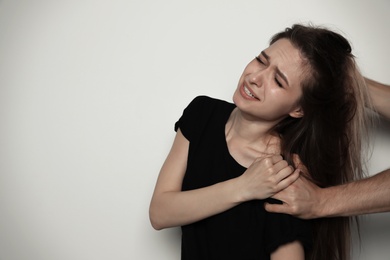 Man fighting with woman on light background, space for text. Stop sexual assault