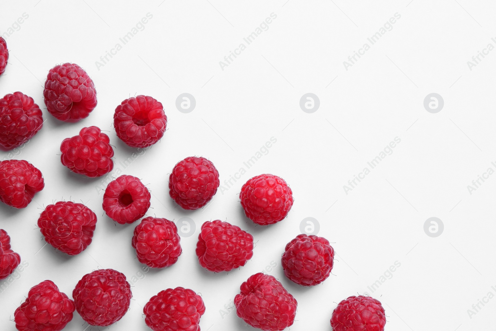 Photo of Tasty ripe raspberries on white background, flat lay. Space for text