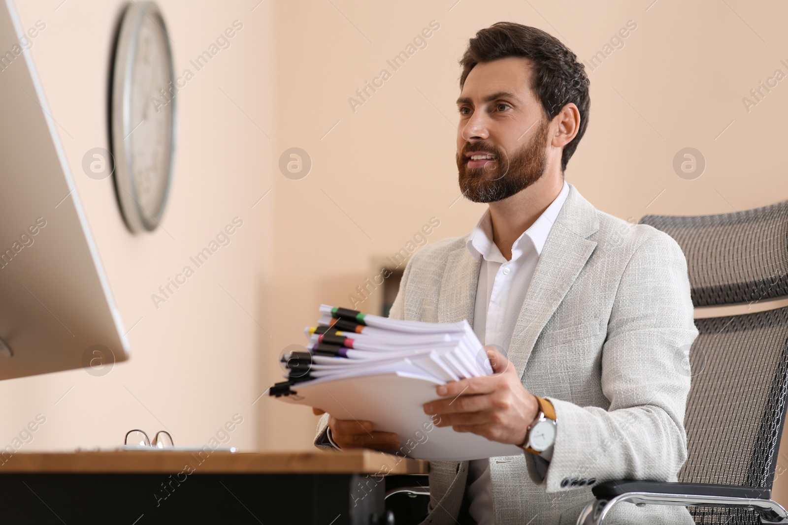 Photo of Businessman with documents at wooden table in office