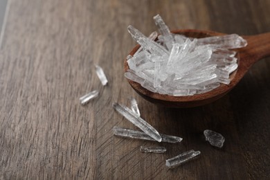 Photo of Menthol crystals on wooden background, closeup. Space for text