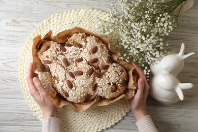 Photo of Woman with delicious Italian Easter dove cake (traditional Colomba di Pasqua) at white wooden table, top view