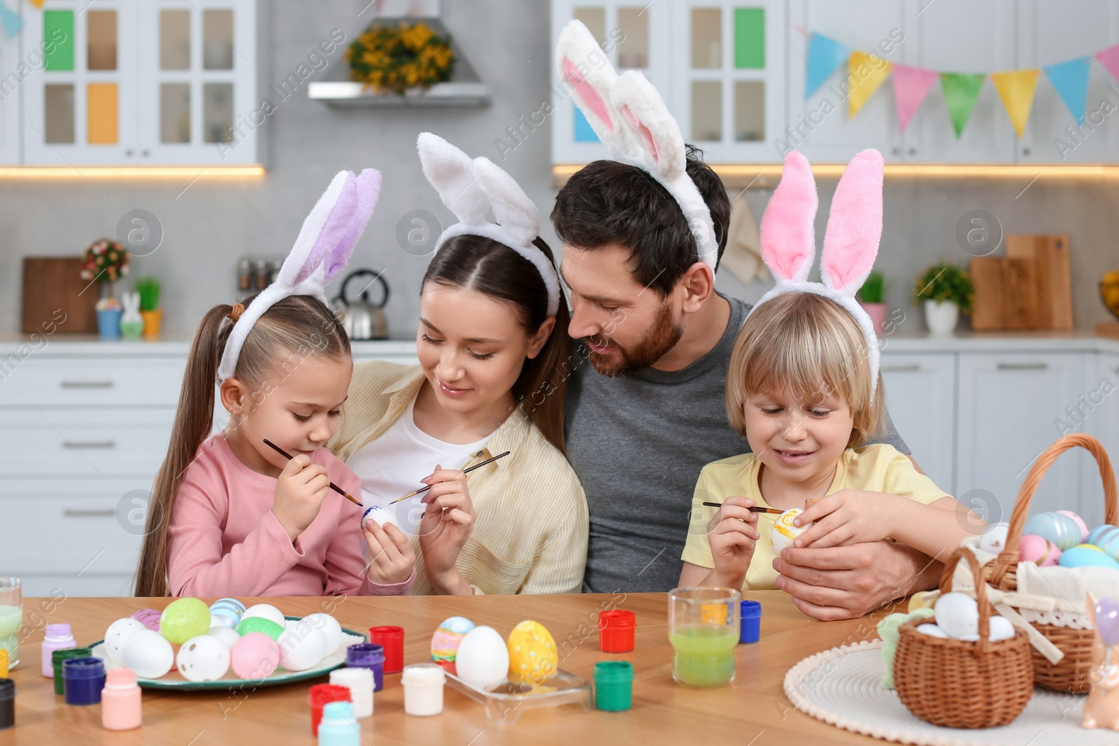 Photo of Happy family painting Easter eggs at table in kitchen