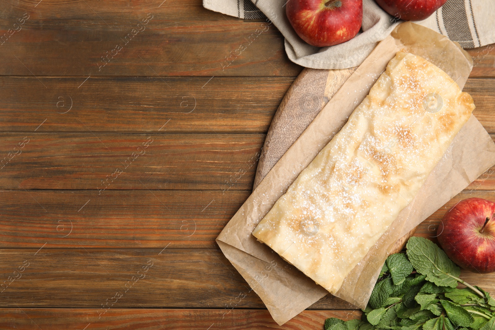 Photo of Delicious strudel, mint and fresh apples on wooden table, flat lay. Space for text