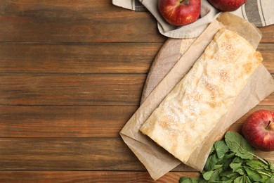 Photo of Delicious strudel, mint and fresh apples on wooden table, flat lay. Space for text