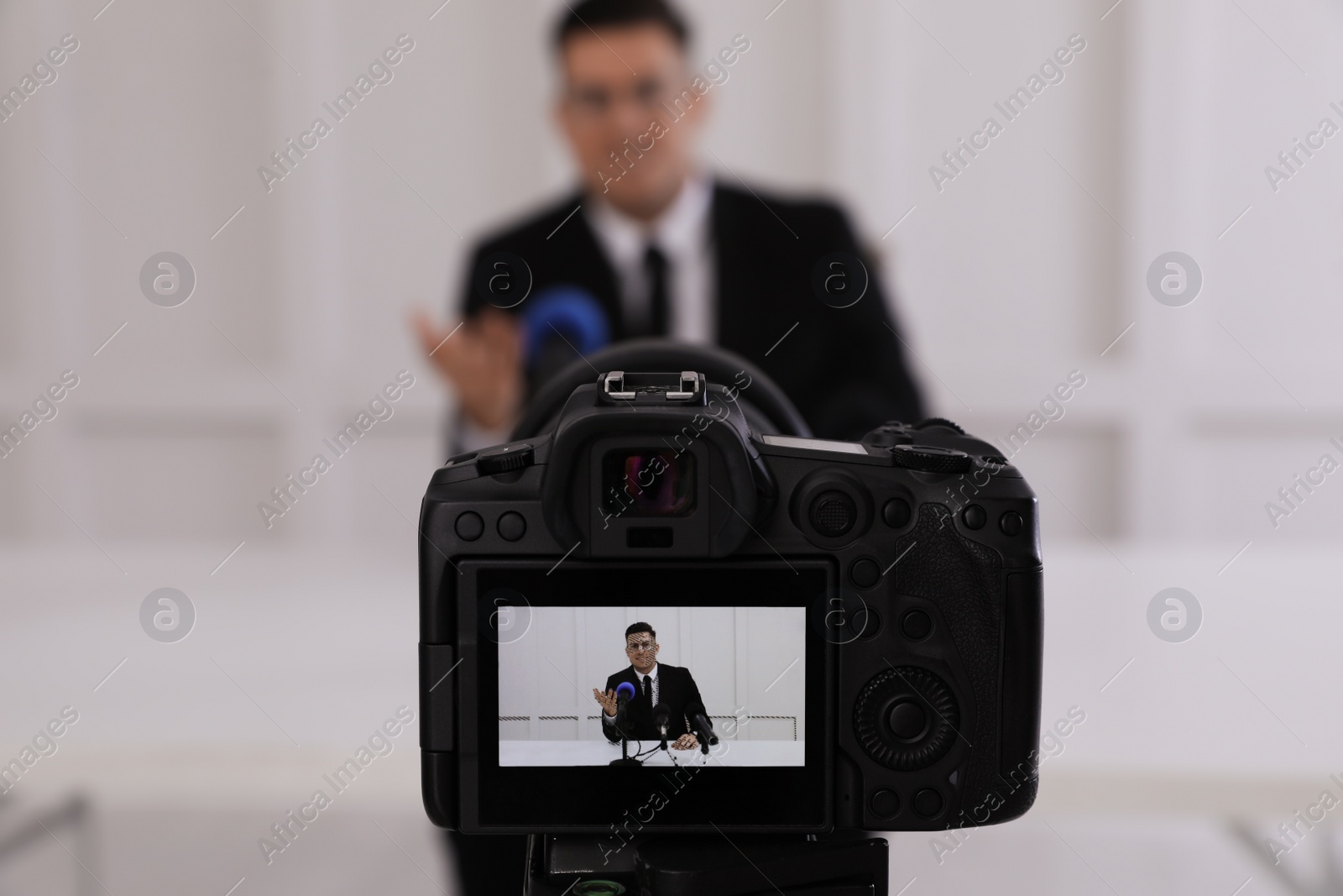 Photo of Business man giving interview at official event, focus on video camera screen