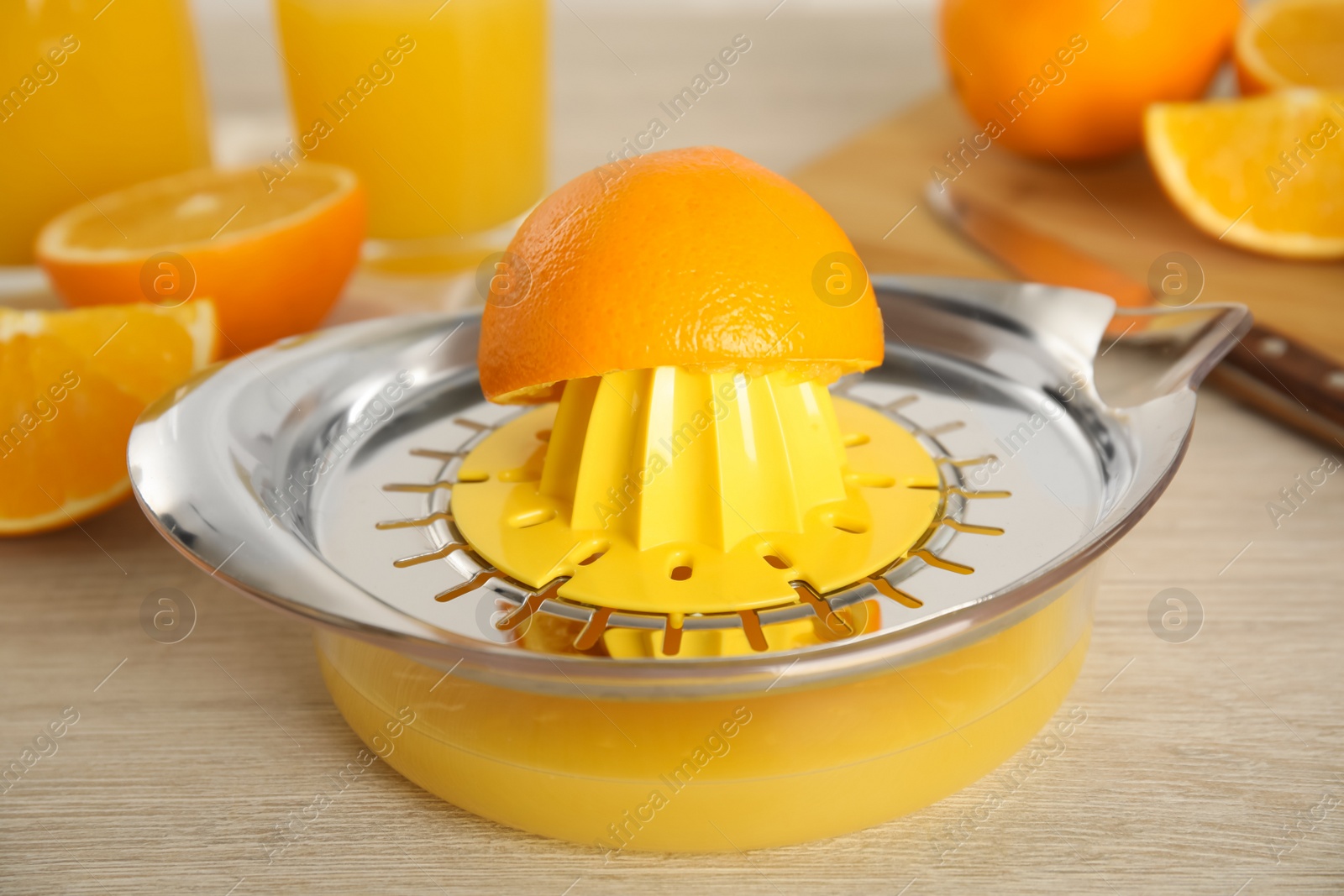 Photo of Cut fresh ripe orange and squeezer on wooden table