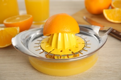 Photo of Cut fresh ripe orange and squeezer on wooden table