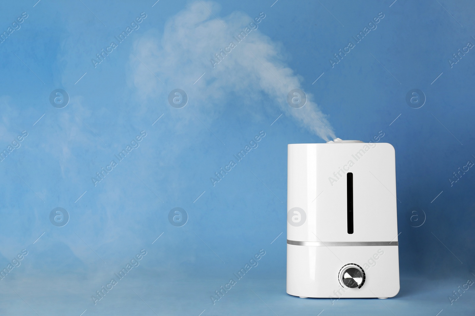 Photo of Modern air humidifier on light blue background. Space for text