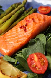 Photo of Tasty grilled salmon with tomatoes, asparagus, lemon and basil, closeup