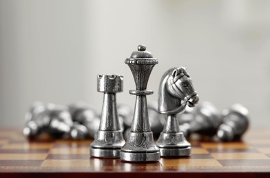 Photo of Silver bishop, knight and rook on wooden chess board, closeup