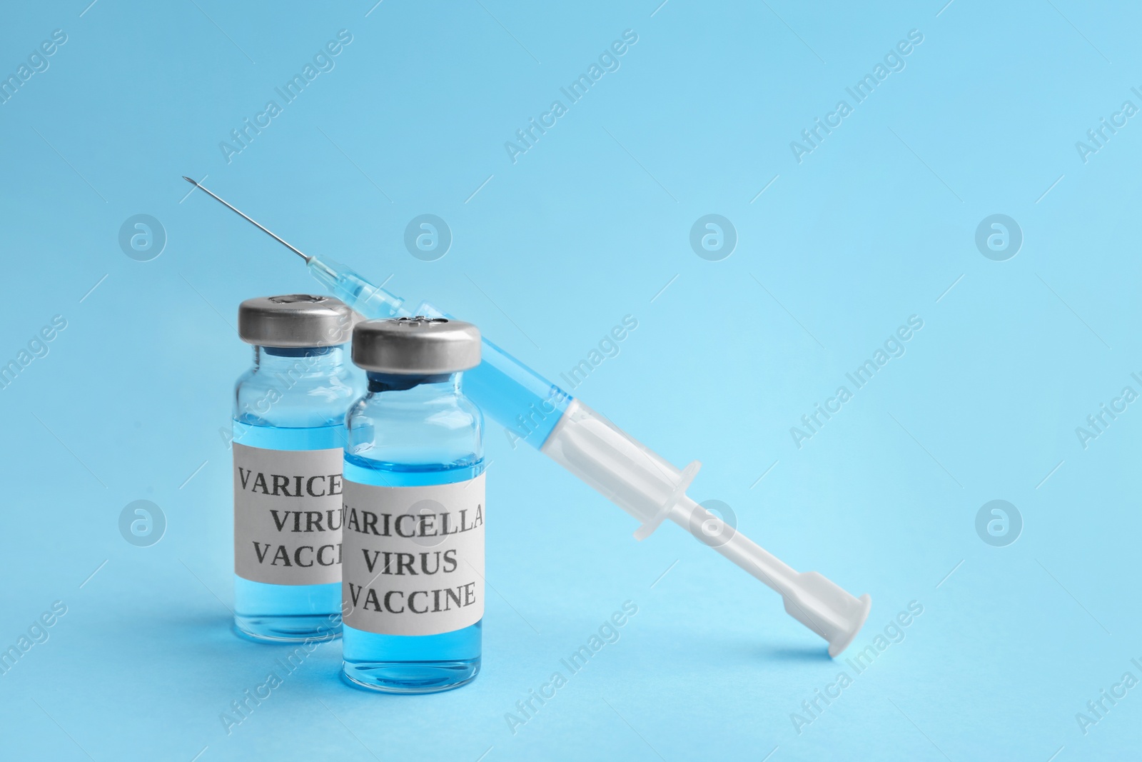 Photo of Chickenpox vaccine and syringe on light blue background. Varicella virus prevention