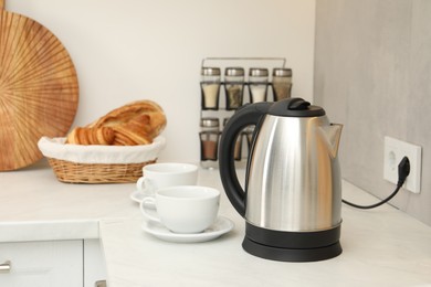 Photo of Electric kettle and cups on counter in kitchen