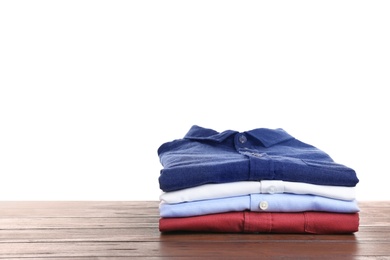 Pile of ironed clothes on table against white background. Space for text