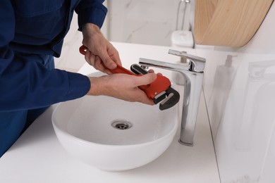 Professional plumber fixing water tap in bathroom, closeup