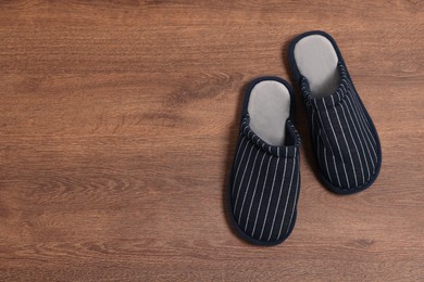 Photo of Pair of stylish slippers on wooden floor, top view. Space for text