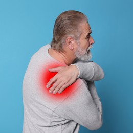 Senior man suffering from rheumatism on light blue background