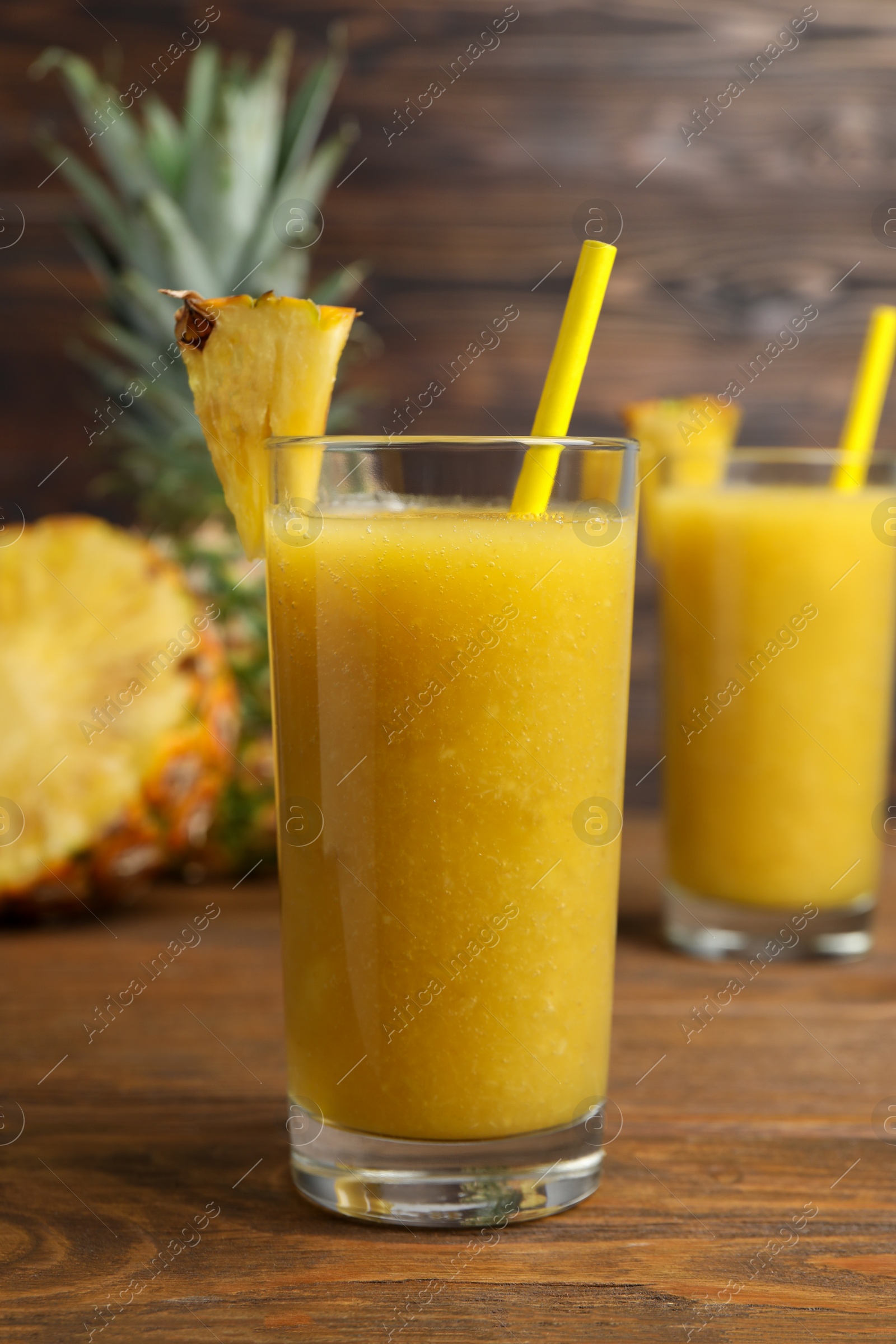Photo of Tasty pineapple smoothie, whole and cut fruit on wooden table