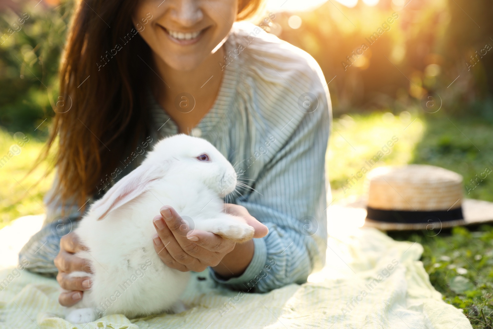 Photo of Happy woman with cute rabbit on green grass outdoors, closeup