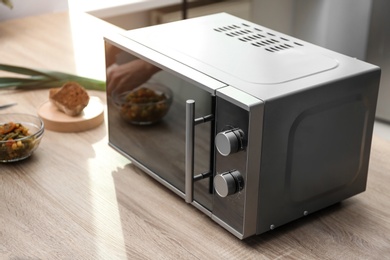 Photo of Modern microwave oven on table in kitchen