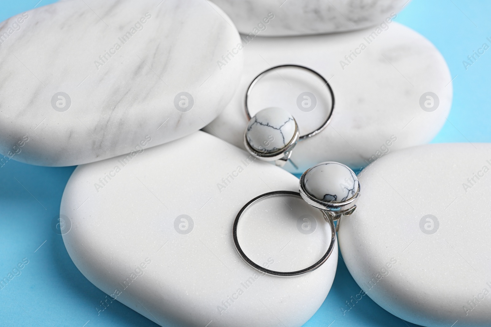 Photo of Elegant earrings and white marble on light blue background. Luxury jewelry