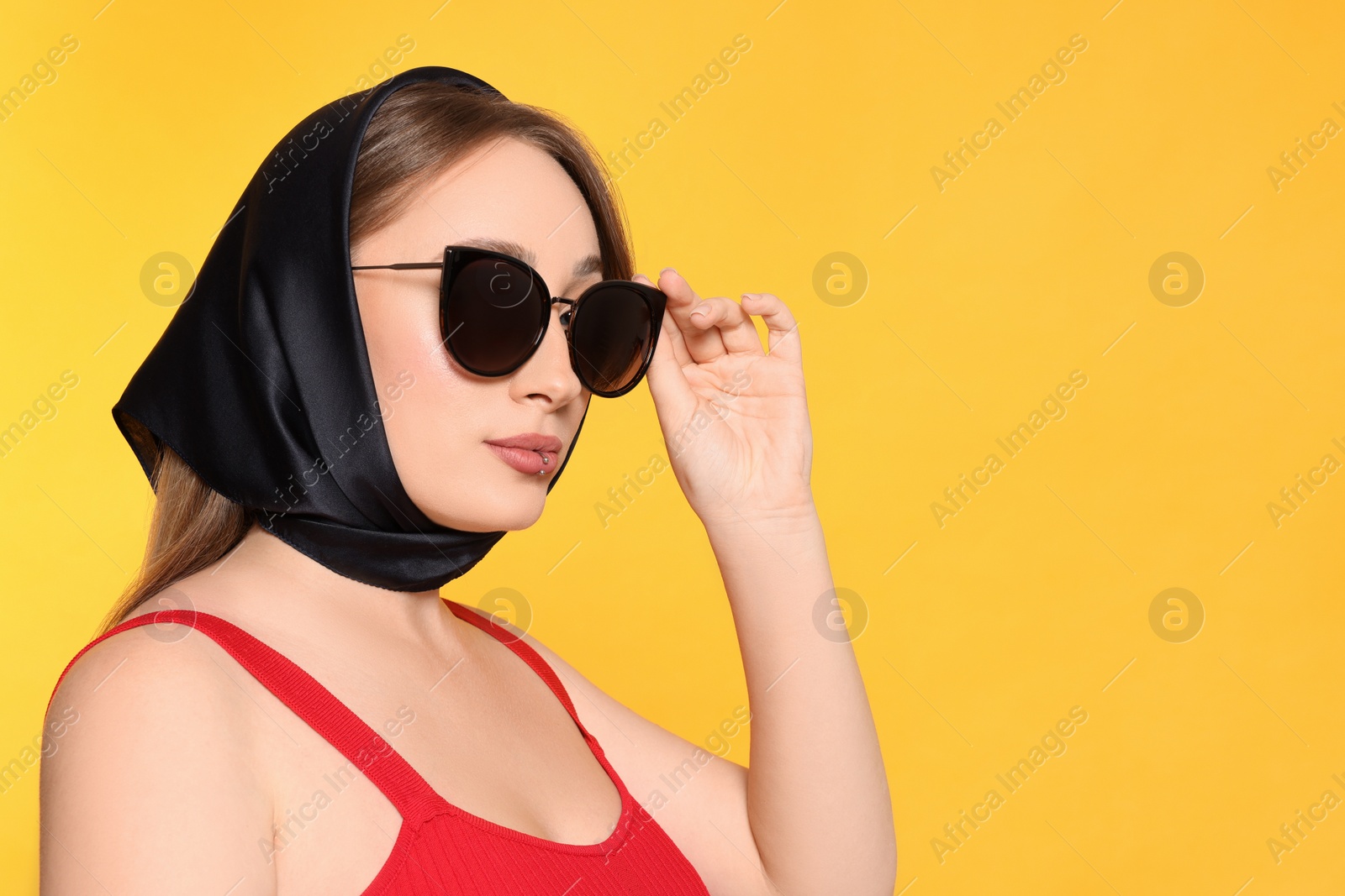 Photo of Young woman with lip piercing and sunglasses on yellow background, space for text