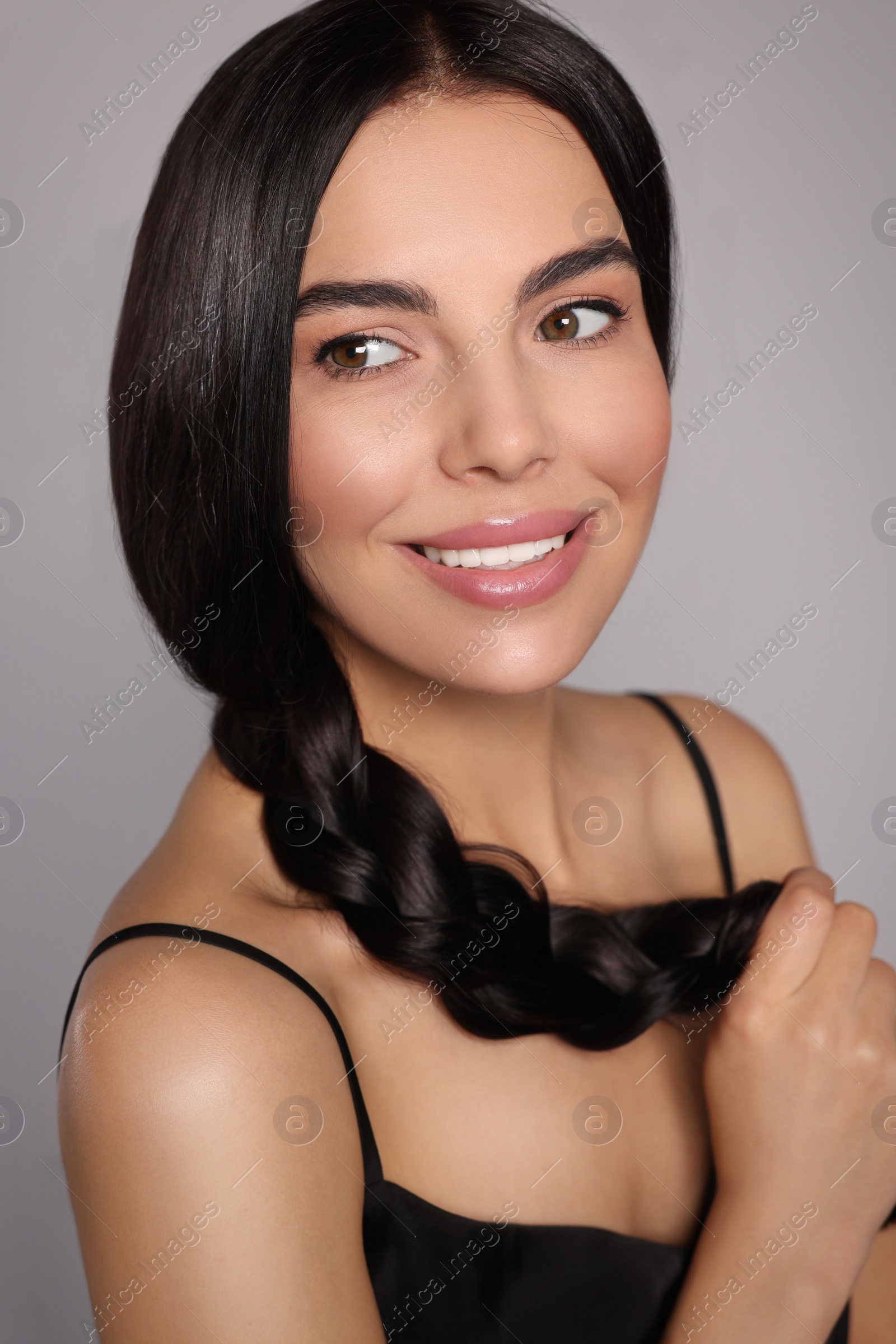 Photo of Portrait of beautiful young woman with healthy strong hair on light grey background