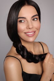 Portrait of beautiful young woman with healthy strong hair on light grey background