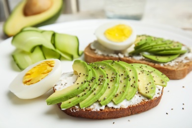 Crisp rye toast with avocado, cream cheese and quail egg on plate, closeup