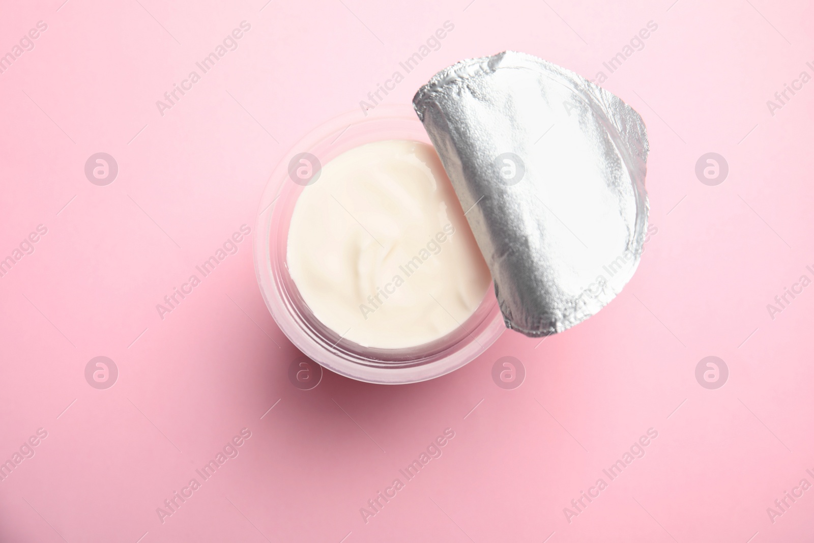 Photo of Plastic cup with creamy yogurt on color background, top view