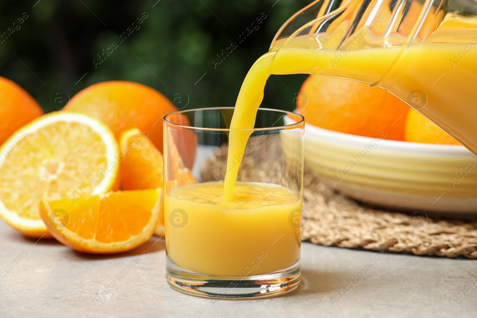 Photo of Pouring orange juice into glass at light table, closeup