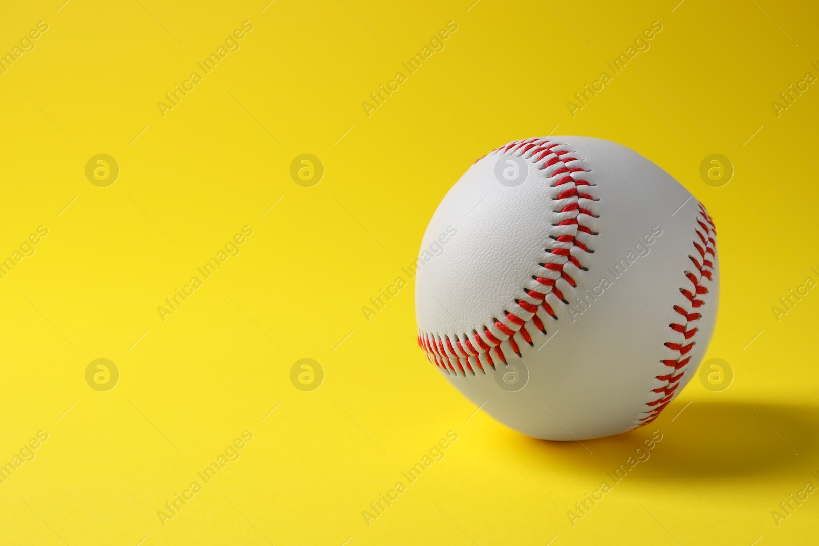Photo of One baseball ball on yellow background. Space for text
