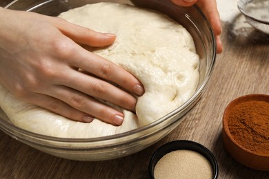Photo of Woman kneading yeast dough for cake at wooden table, closeup