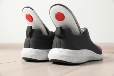 Orthopedic insoles in shoes on floor, closeup