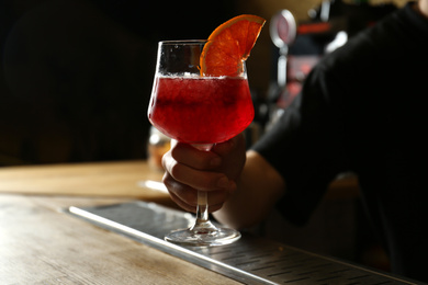 Bartender holding glass of fresh alcoholic cocktail in bar, closeup