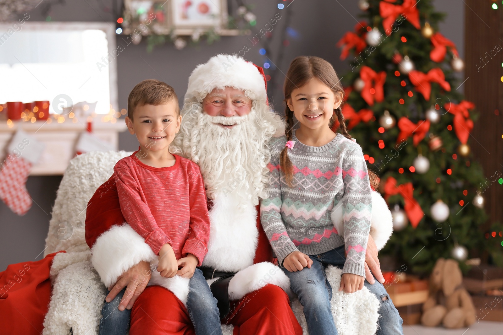 Photo of Little children sitting on authentic Santa Claus' knees indoors