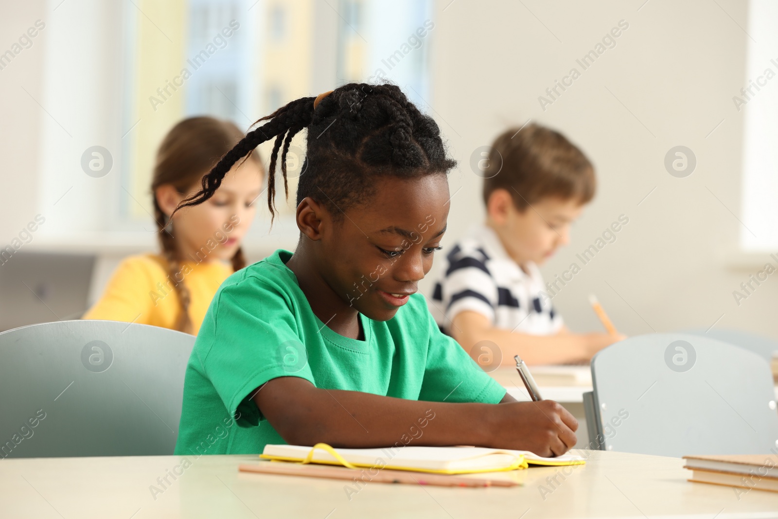 Photo of Cute little boy studying in classroom at school