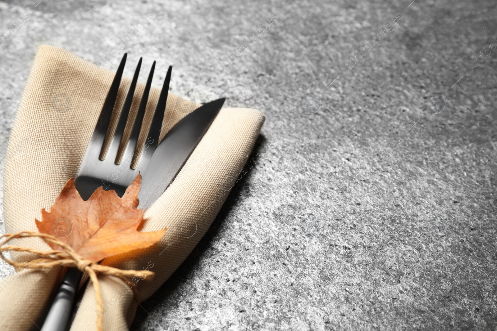Photo of Cutlery and autumn leaf on grey background, closeup with space for text. Thanksgiving Day celebration