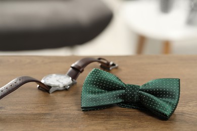 Photo of Stylish green bow tie and wristwatch on wooden table