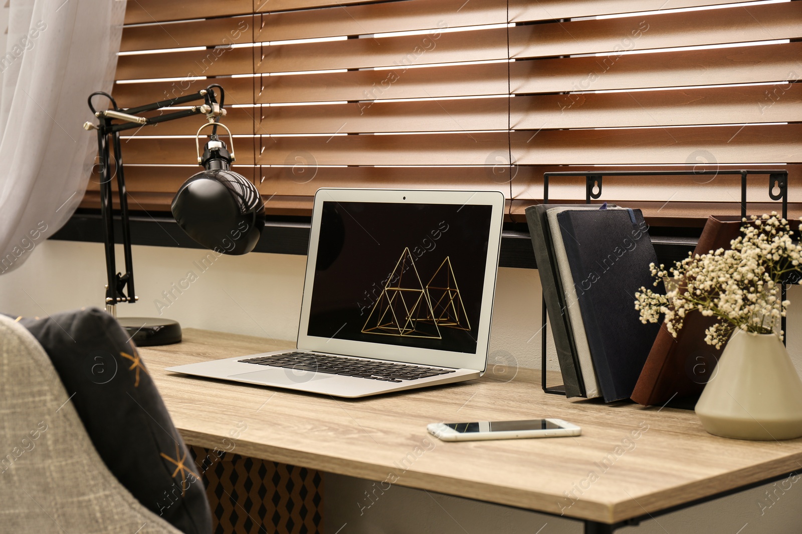 Photo of Comfortable workplace near window with horizontal wooden blinds