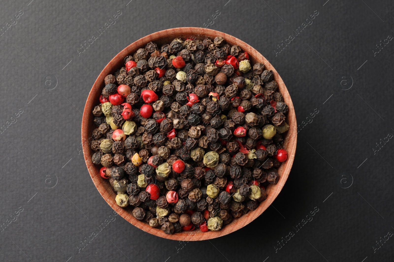 Photo of Bowl with peppercorn mix on grey background, top view
