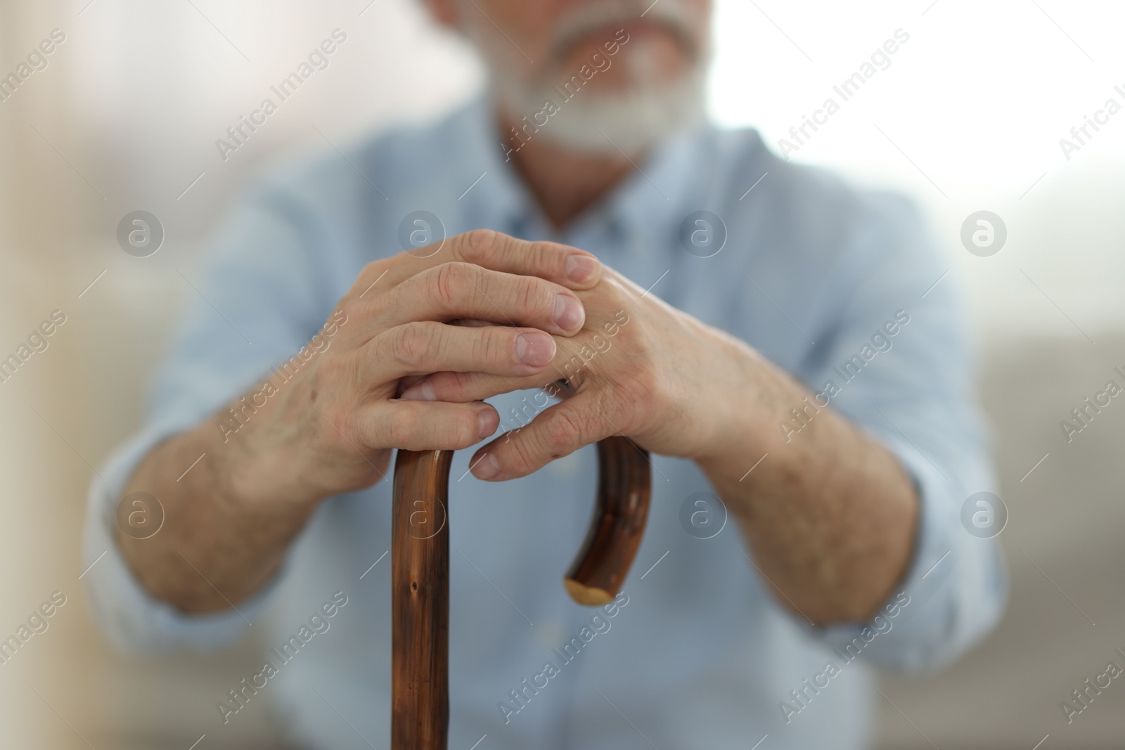 Photo of Grandpa with wooden walking cane indoors, closeup