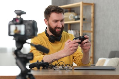 Photo of Smiling technology blogger recording video review about game controllers at home