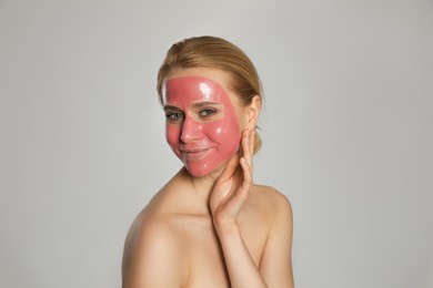 Photo of Young woman with pomegranate face mask on light grey background