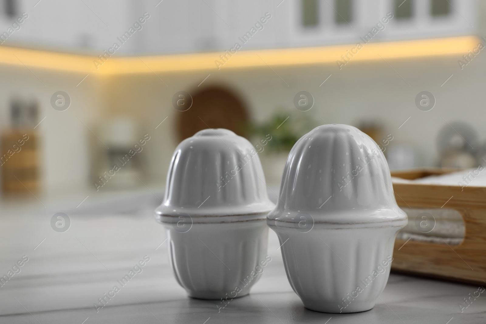 Photo of Ceramic salt and pepper shakers on white marble table in kitchen