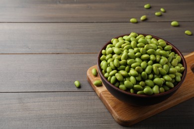 Photo of Bowl of delicious edamame beans on wooden table, space for text