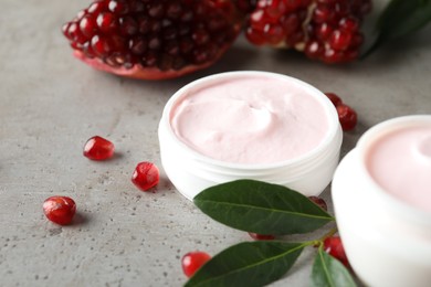 Natural facial mask, pomegranate seeds and green leaves on light grey table, closeup