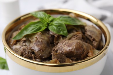Photo of Delicious fried chicken liver with onion and basil in bowl on table, closeup