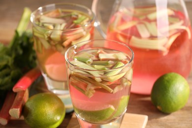 Photo of Tasty rhubarb cocktail with lime on wooden table, closeup