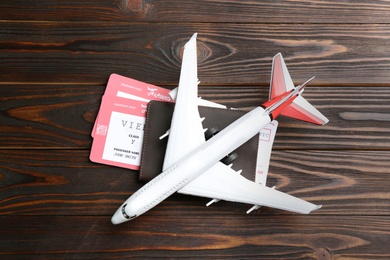 Photo of Toy airplane and passport with tickets on wooden background, flat lay